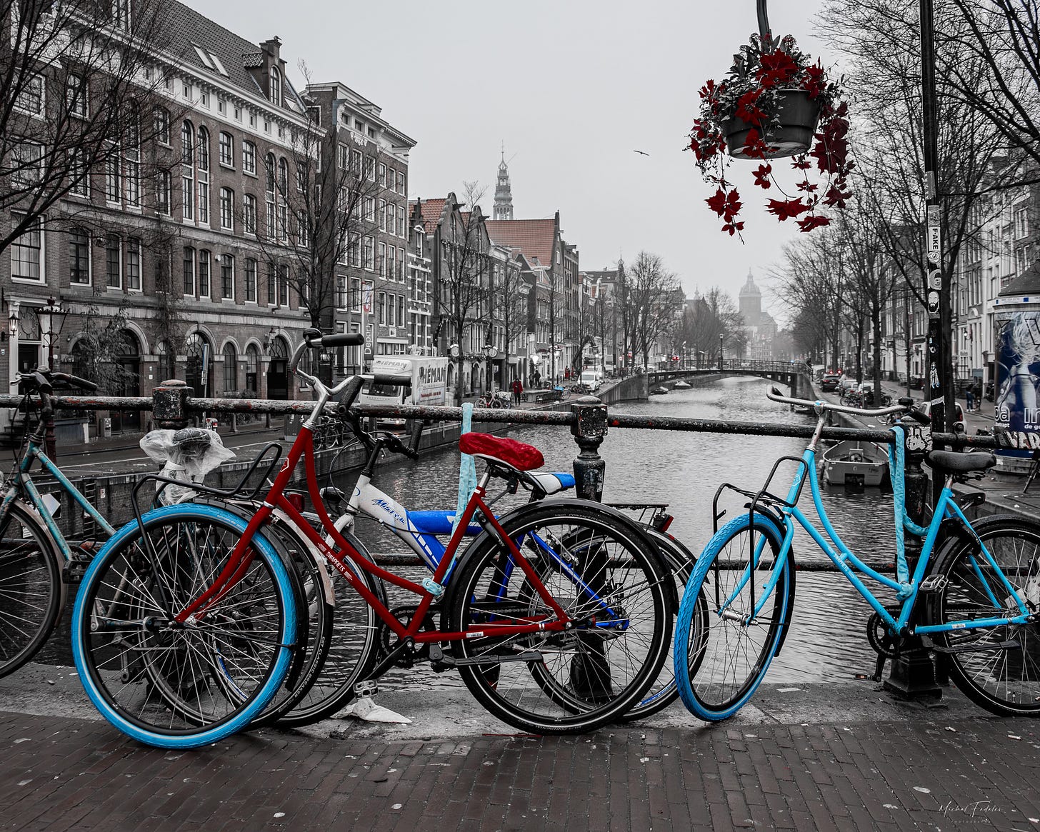 Red and blue bicycles placed against a railing on a bridge over a canal in Amsterdam Red and blue bicycles placed against a railing on a bridge over a canal in Amsterdam