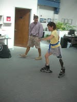 Me, trying to skate with a prosthetic on the carpet of Prosthetic Innovations in the fall of 2011.  Prosthetist Tim is close by, looking on.  I'm wearing a gait belt.
