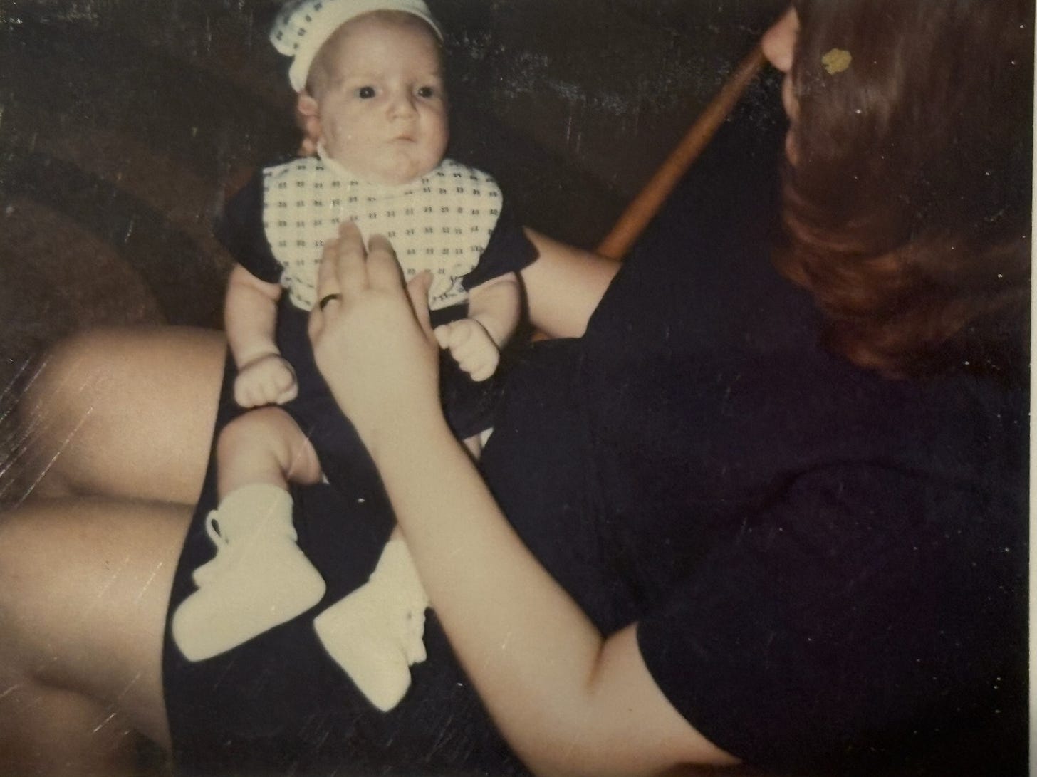A young mother holding her baby on her lap.