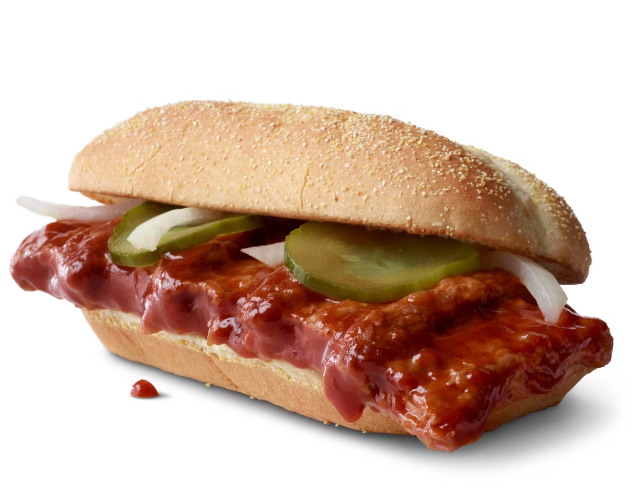 A three quarter view photograph of a McRib sandwich, showing a slab of meat slathered in red sauce with two pickle slides and some strips of raw, white onion on a French roll.