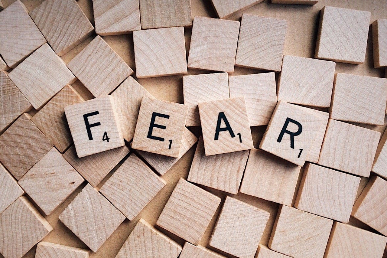 A set of wooden scrabble letters, mostly face down, the top four reading FEAR A set of wooden scrabble letters, mostly face down, the top four reading FEAR