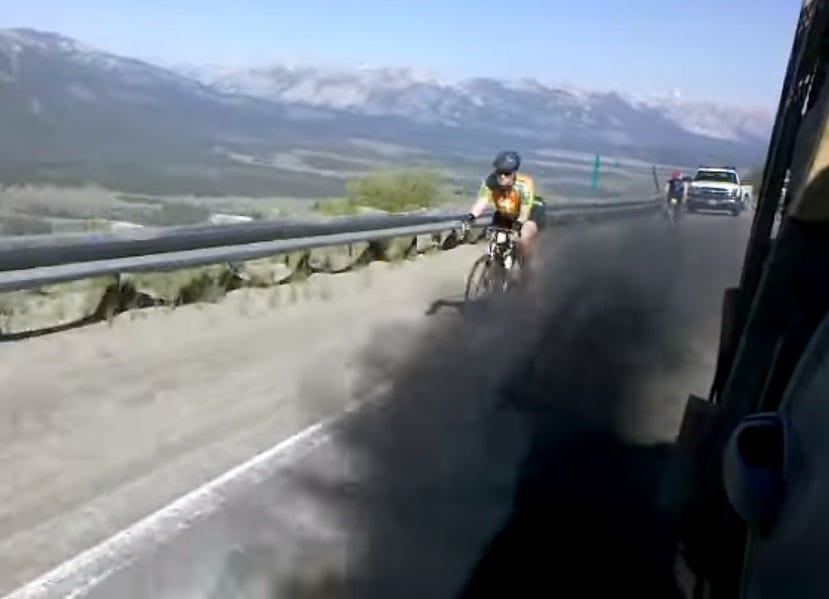 A diesel pickup blows thick black exhaust smoke into the face of a bicyclist on a mountain road. That'll learn 'im. A diesel pickup blows thick black exhaust smoke into the face of a bicyclist on a mountain road. That'll learn 'im.