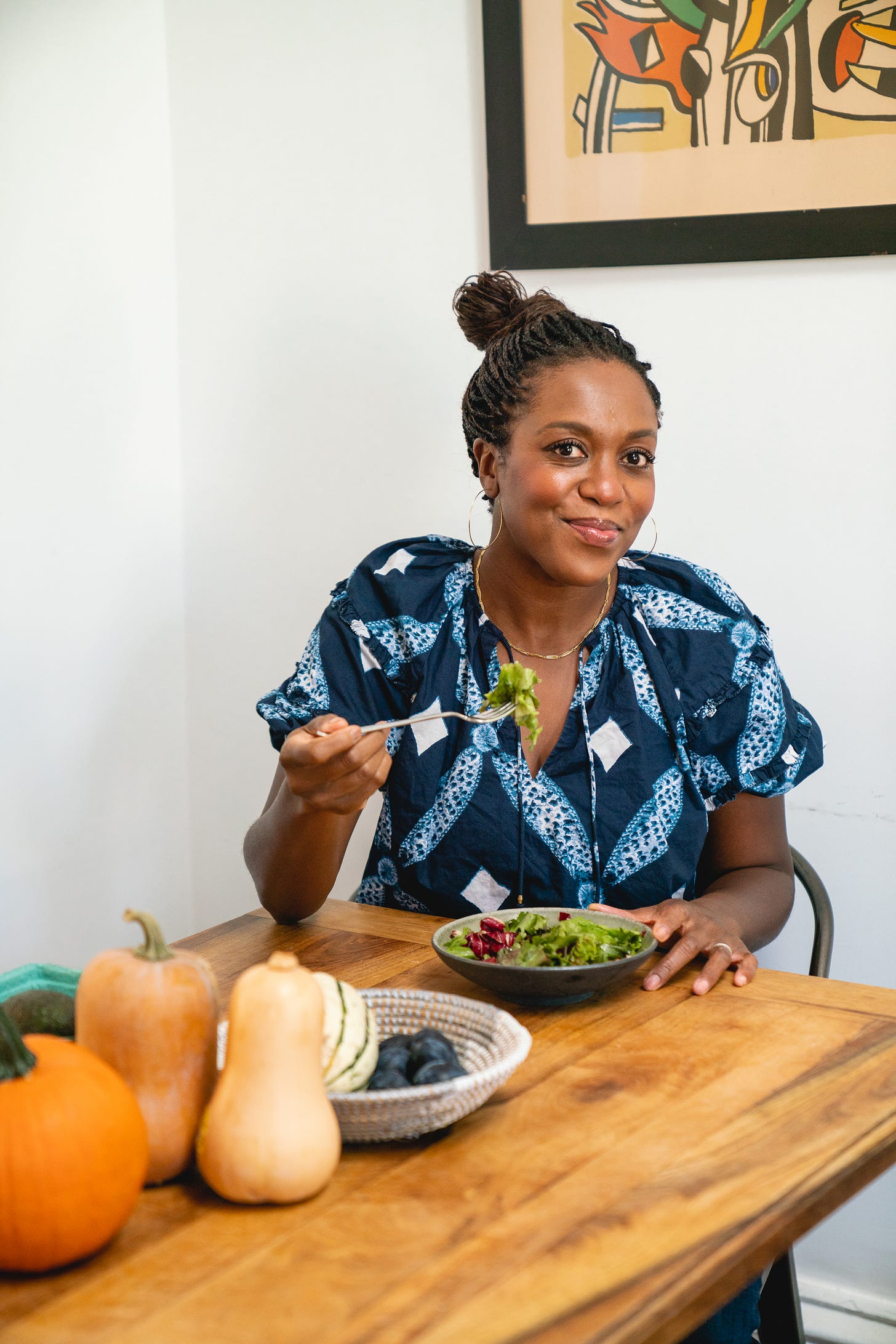 Maya Feller sitting at a wood table eating a salad Maya Feller sitting at a wood table eating a salad