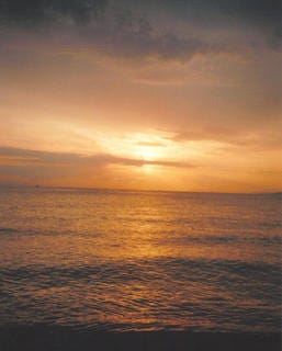 Three images of the sunset over a beach. The final image features sun rays scattered across the clouds
