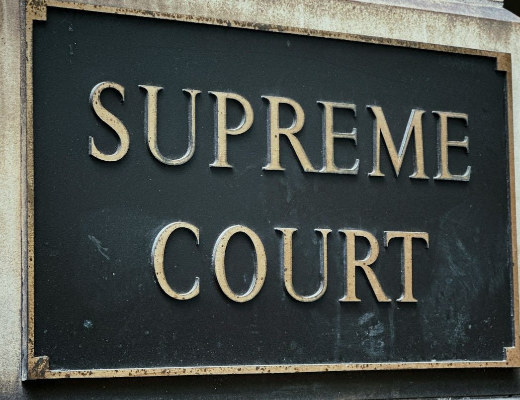 a black and gold sign that says supreme court a black and gold sign that says supreme court