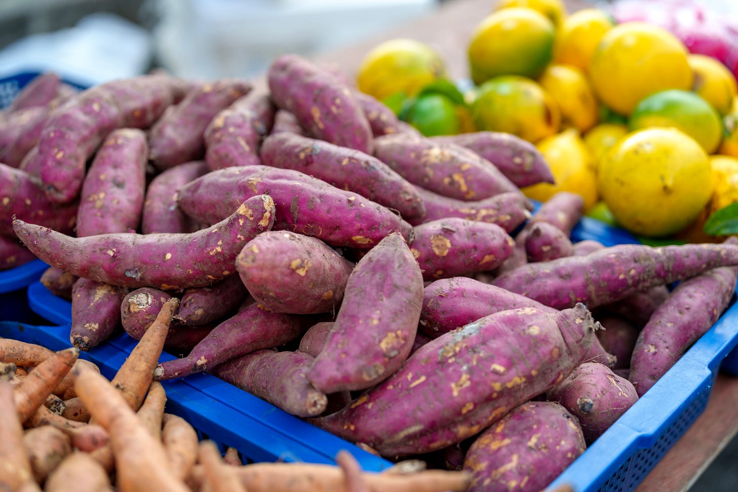 Sweet potatoes and fruit at a farm stand.