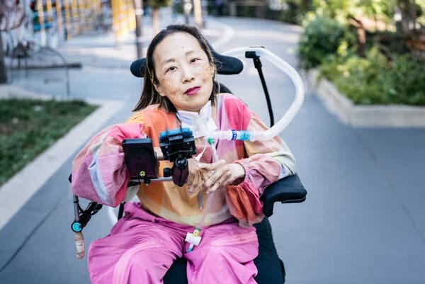A woman in a wheelchair with tubes that go into her body.