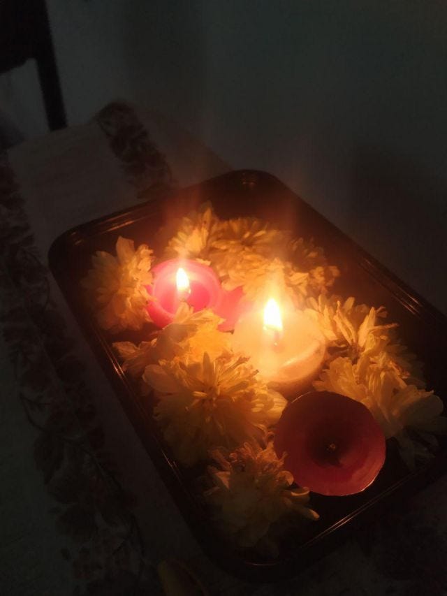 Three candles, two lit, in a bowl of yellow flowers. Three candles, two lit, in a bowl of yellow flowers.