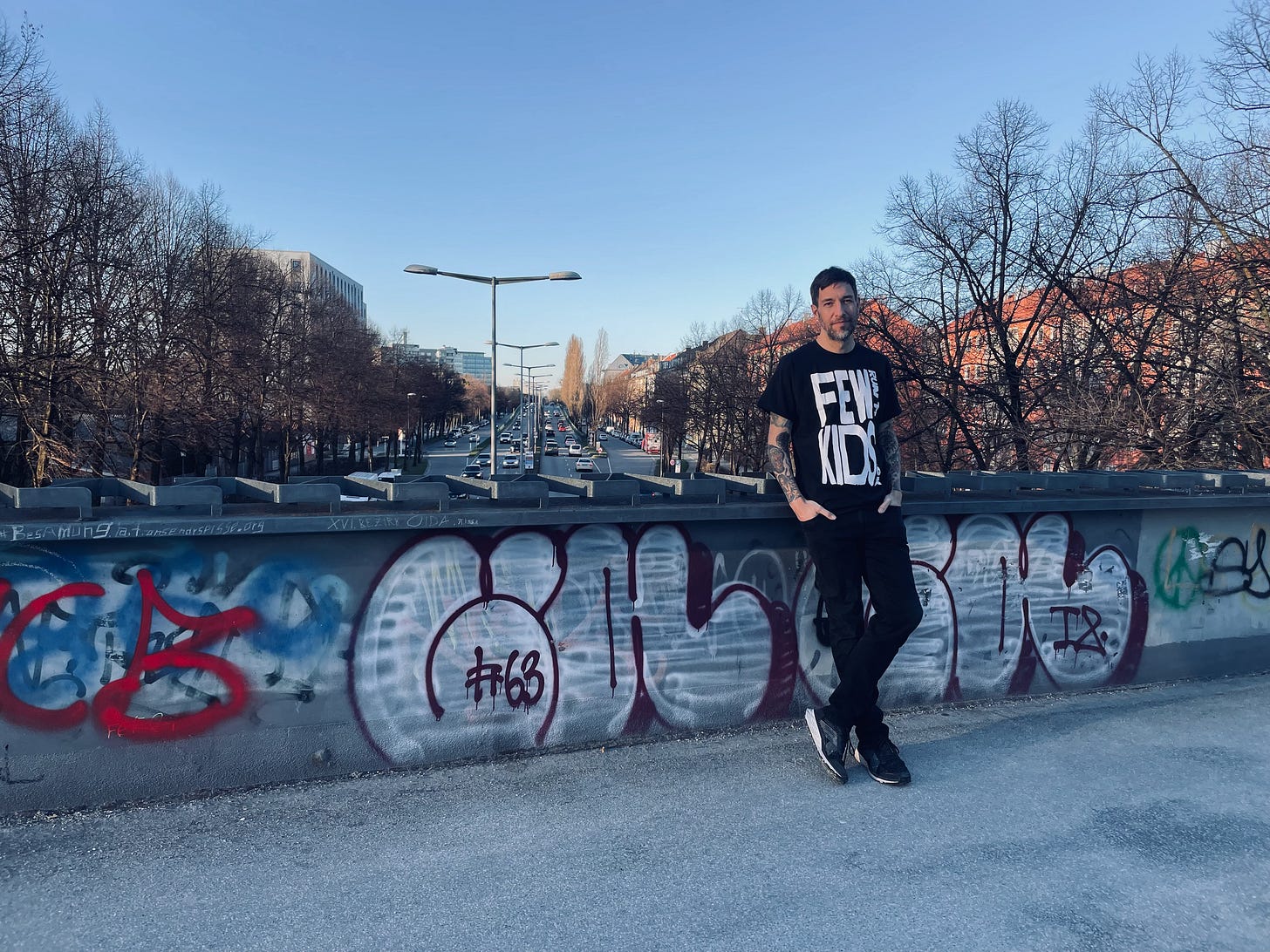 the author standing on a bridge wearing a "few kids run the block" t-shirt