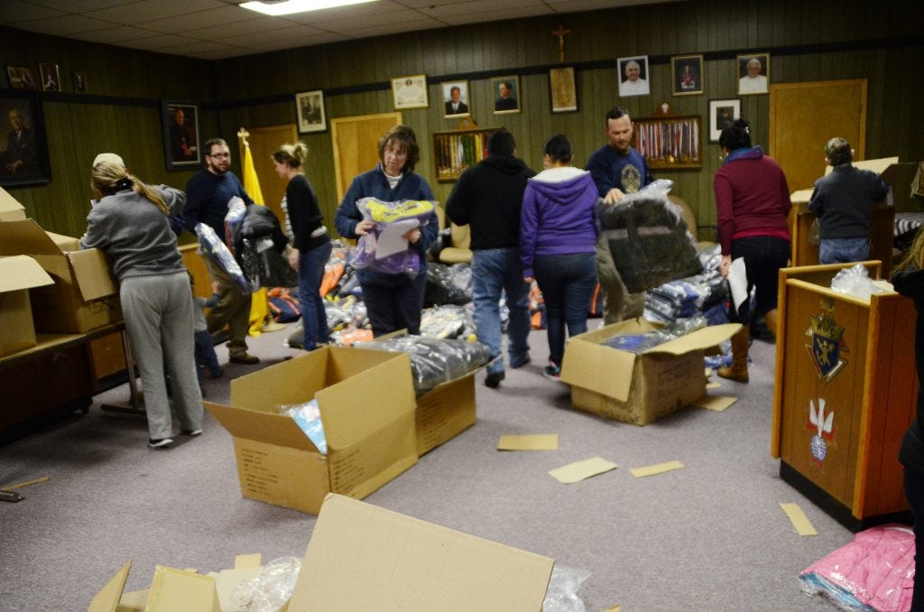 Volunteers sort and carry boxes of new coats at the Knights of Columbus building in Gallup.