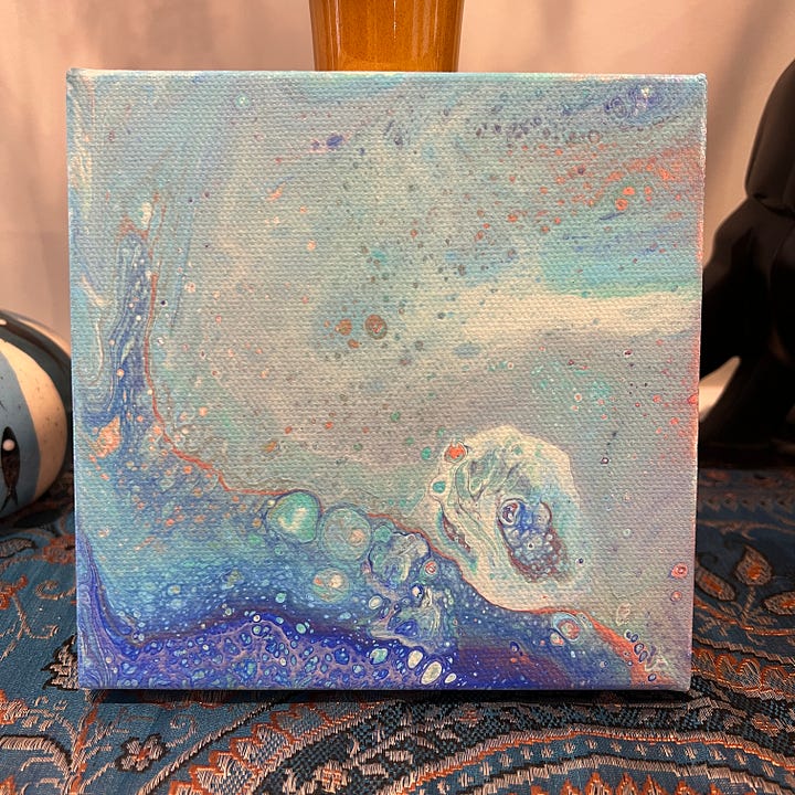 Two small paintings made using poured acrylic paint. One is mostly red and the other is mostly blue.