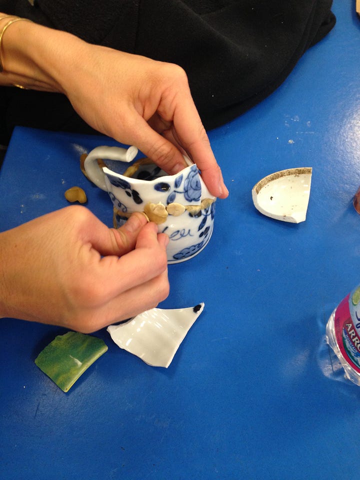broken cups and plates are sorted and reassembled using wax, tape and fiber