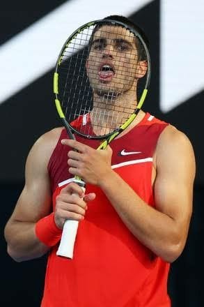 This may contain: a man holding a tennis racquet on top of a tennis ball racket