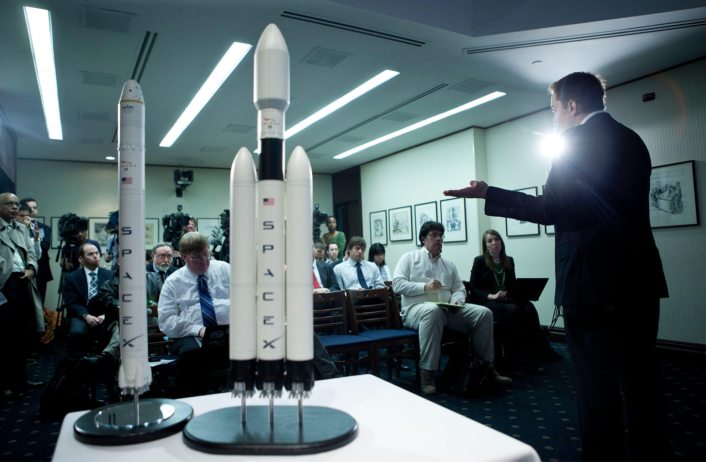 Elon Musk presenting SpaceX rocket models to a room of press, early 2000s Elon Musk presenting SpaceX rocket models to a room of press, early 2000s