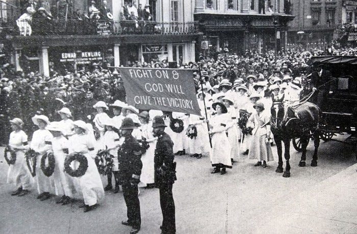 Emily Davison's funeral. Women hold a banner reading "Fight On & God Will Give The Victory," while police look on.