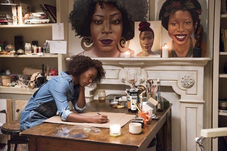 This may contain: a woman sitting at a desk in front of some pictures This may contain: a woman sitting at a desk in front of some pictures