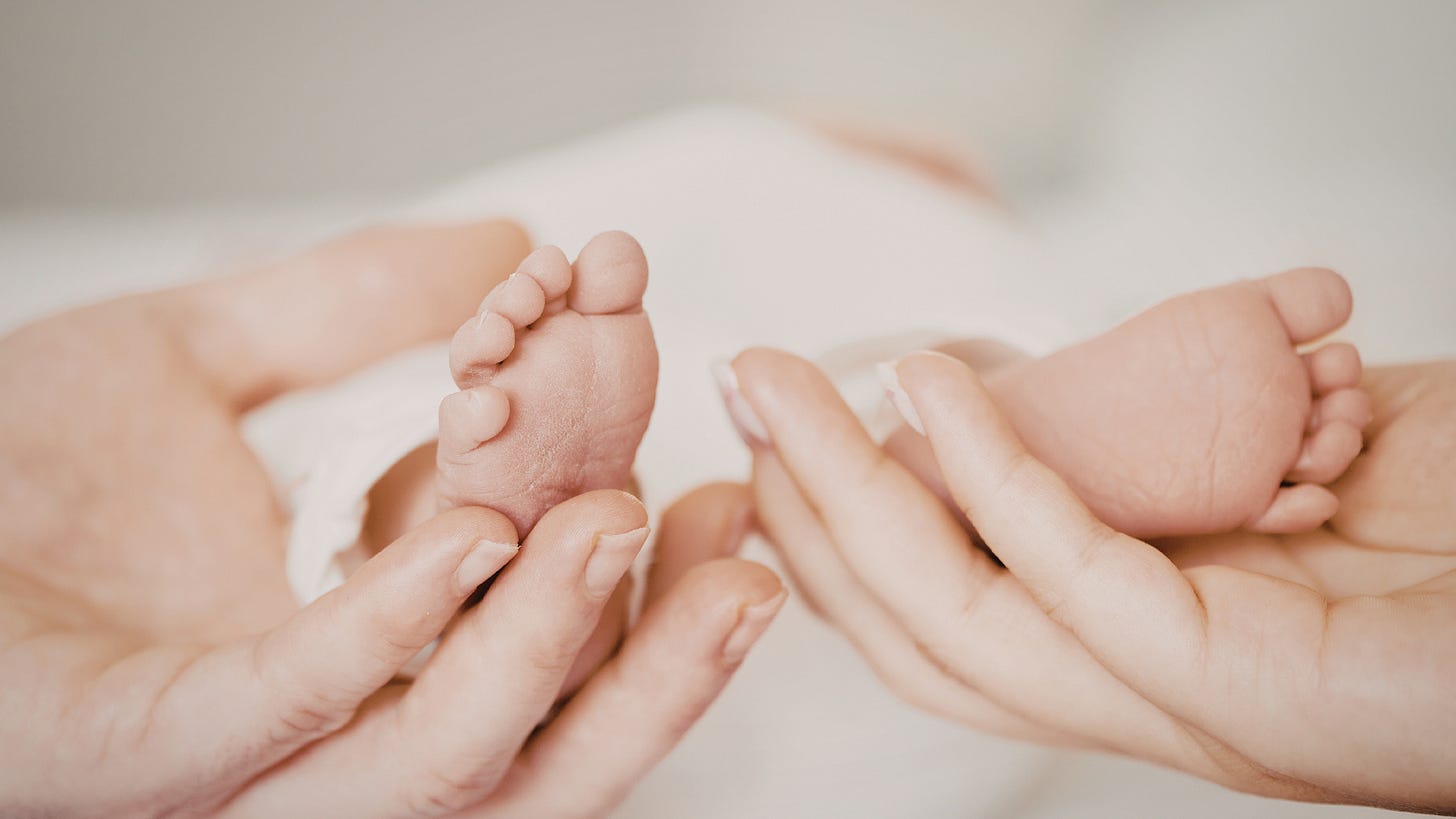 Close up of newborn baby feet held gently by adult hands symbolizing the emotional journey and trust involved in surrogacy and family building