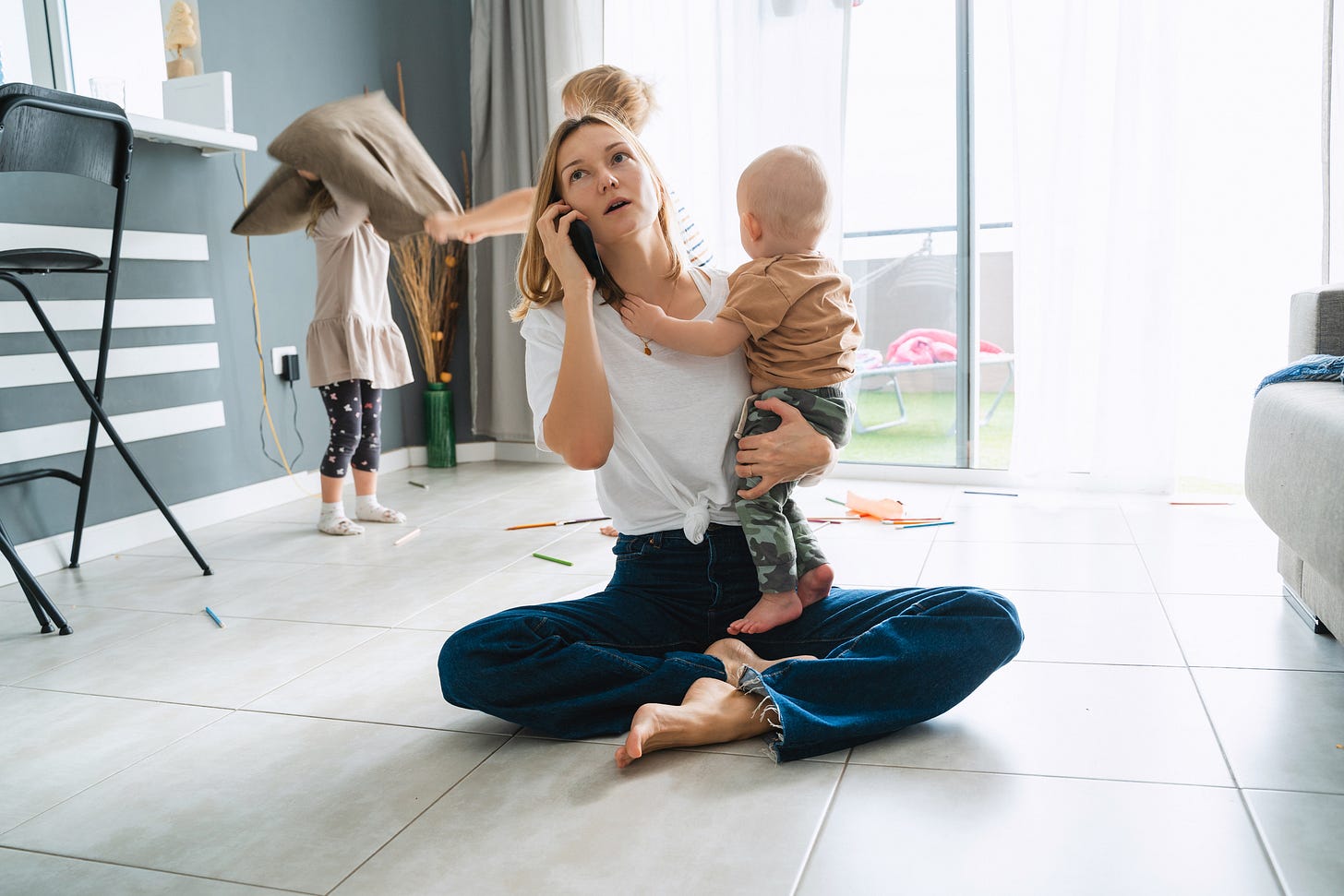 Working mom on the phone with young kids playing around her