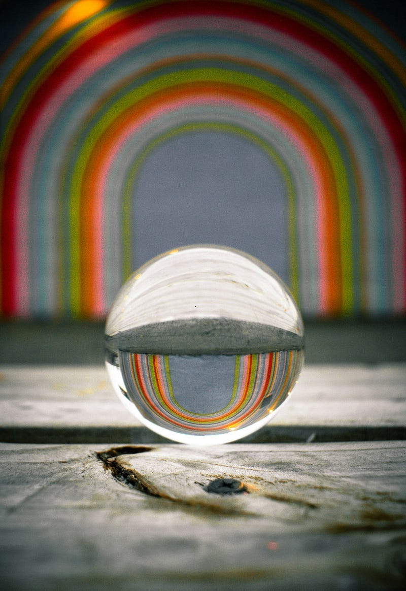 A glass sphere that reflects a multicoloured archway.