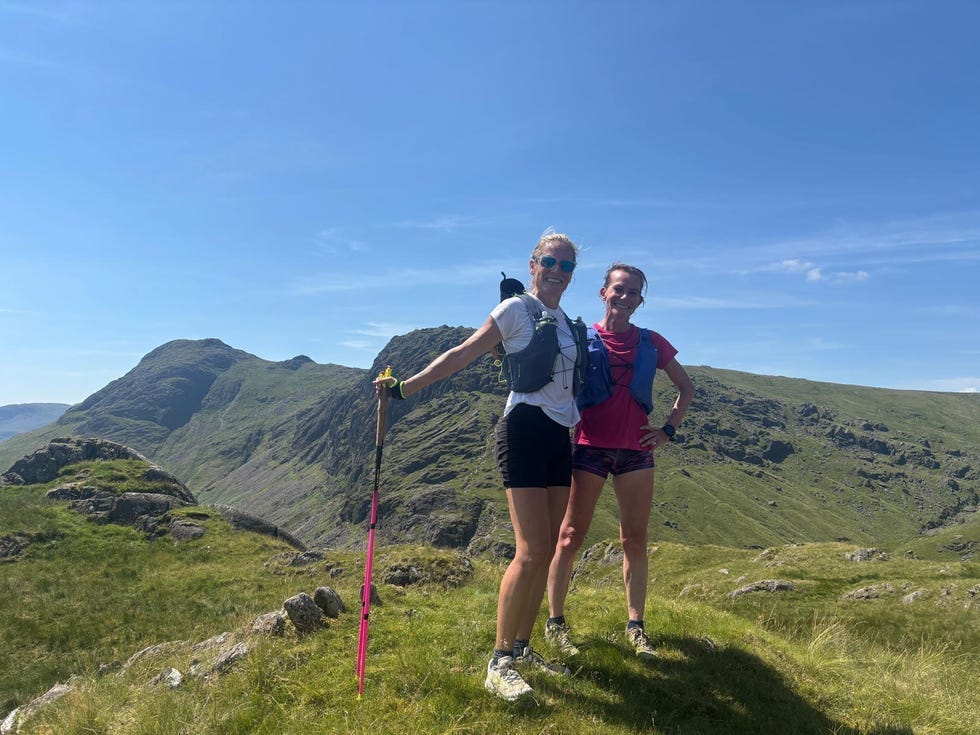 two hikers smiling on a sunny mountain trail