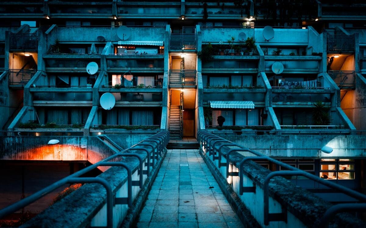An exterior image of the all-concrete Alexandra Road Estate in London, lit with a blue tint at night