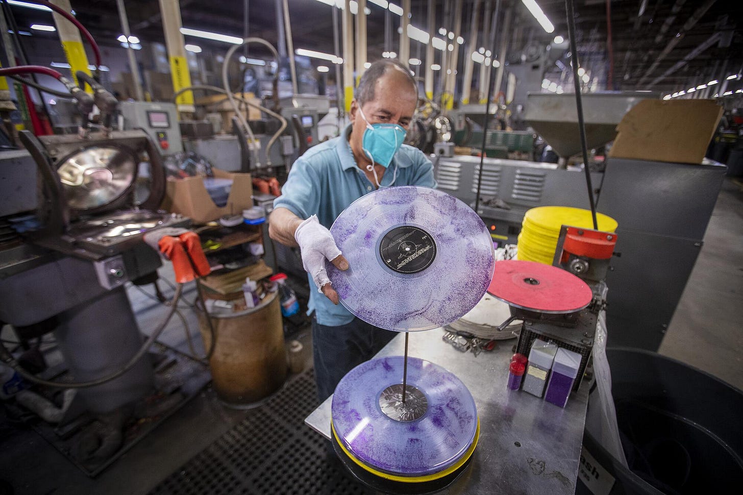 A man stacking vinyl albums onto a spindle to cool.
