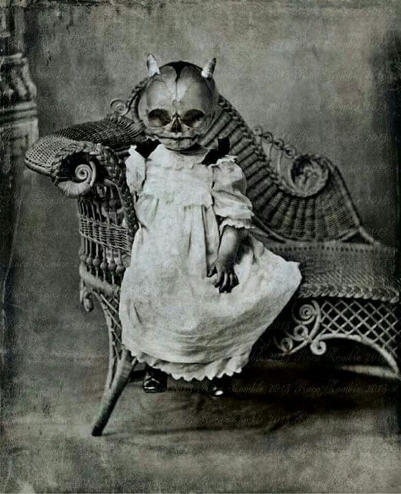 Victorian era Halloween costume of a small child in a nightdress with a skull mask and horns.