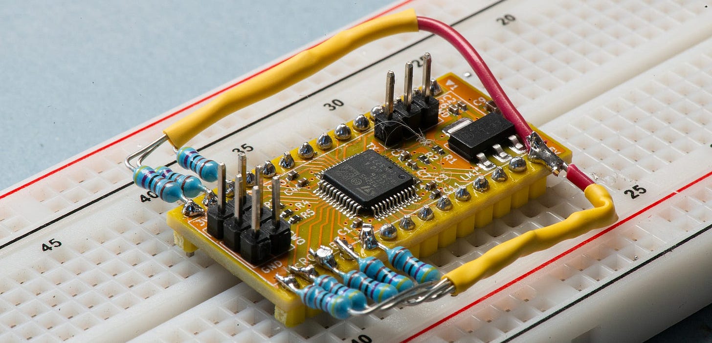 Photograph of a yellow circuit board inserted into a breadboard and with eight external resistors crudely soldered on.