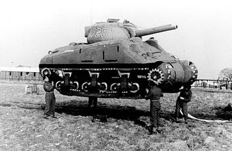 Soldiers lift up an inflatable rubber dummy tank in England. 1939.