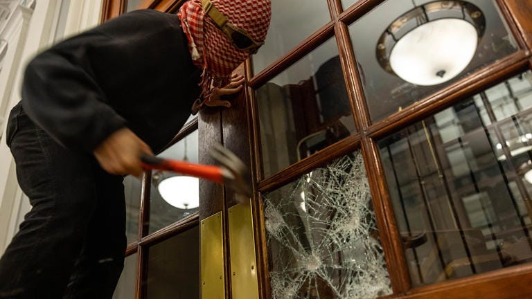 A masked figure smashes a window to get inside Hamilton Hall at Columbia University in New York City on April 30, 2024. Getty Images