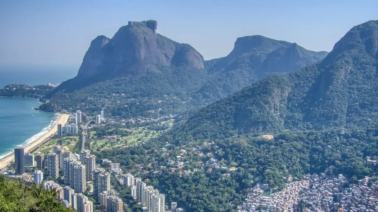 View of rainforest-covered hillsides, high-rise buildings, beach and sea