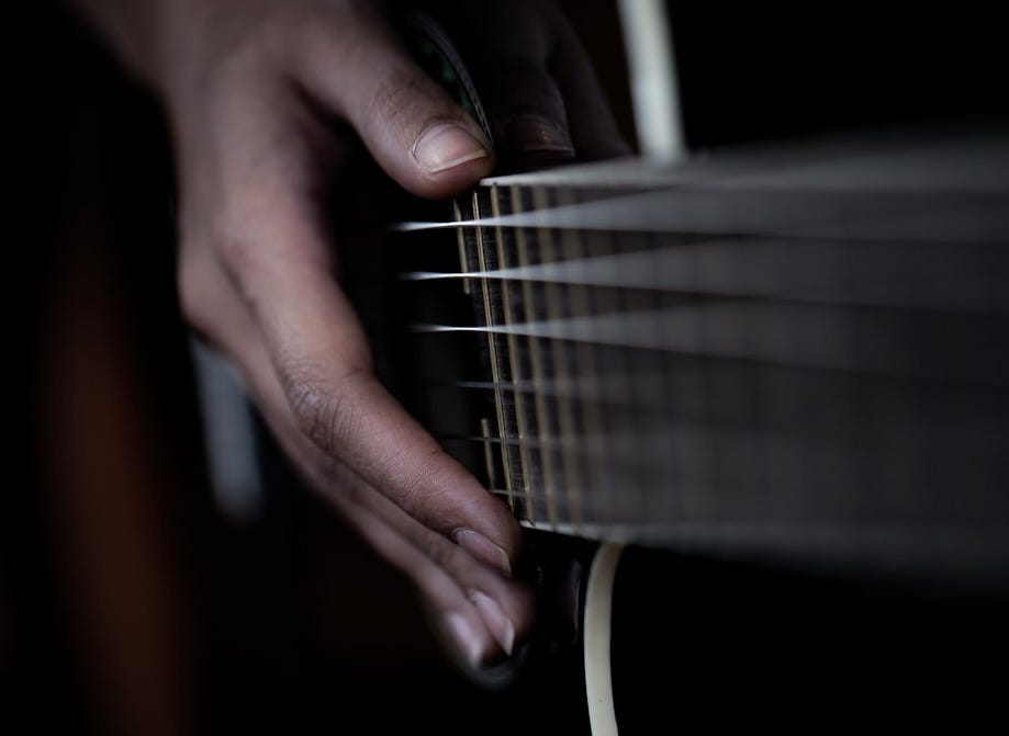 Hand strumming strings of an acoustic guitar