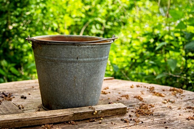 Grey metal pail outdoors sitting on rustic wood surface