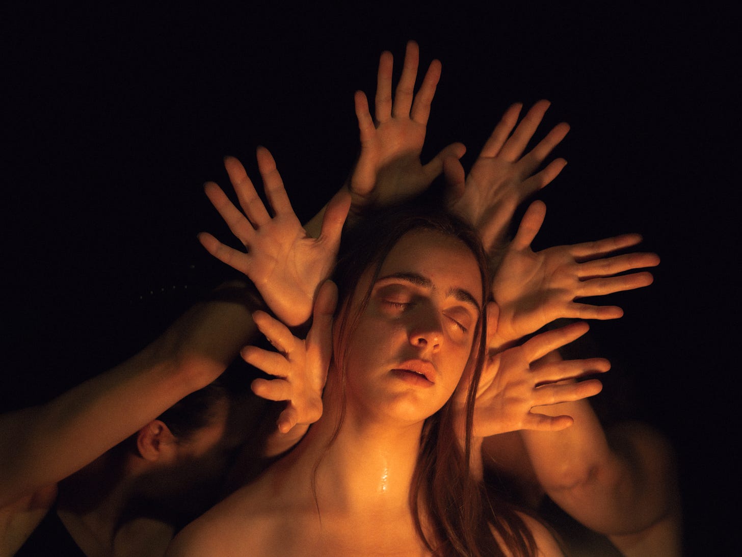 A woman's face, framed by fingers like a crown.