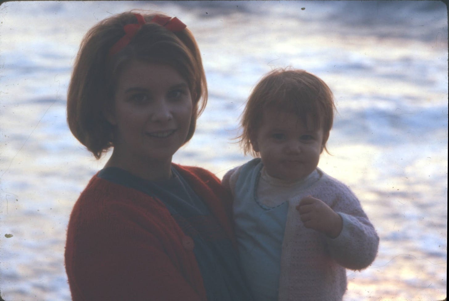 My mother and me at Santa Monica Beach in 1967. The ocean is behind us. My mother smiles at my father, who is holding the camera.
