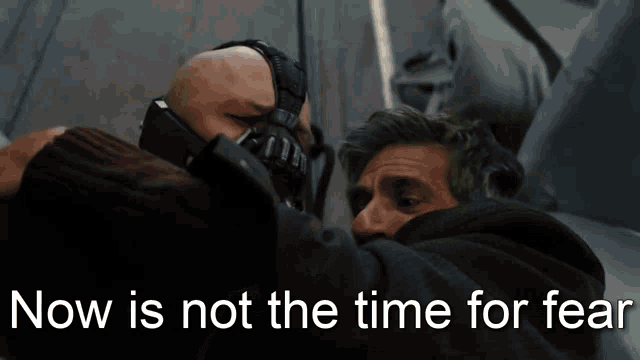 a man wearing a mask is hugging another man with the words now is not the time for fear written below him a man wearing a mask is hugging another man with the words now is not the time for fear written below him