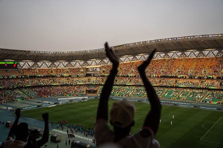 A person raising their hands in the air in a stadium A person raising their hands in the air in a stadium