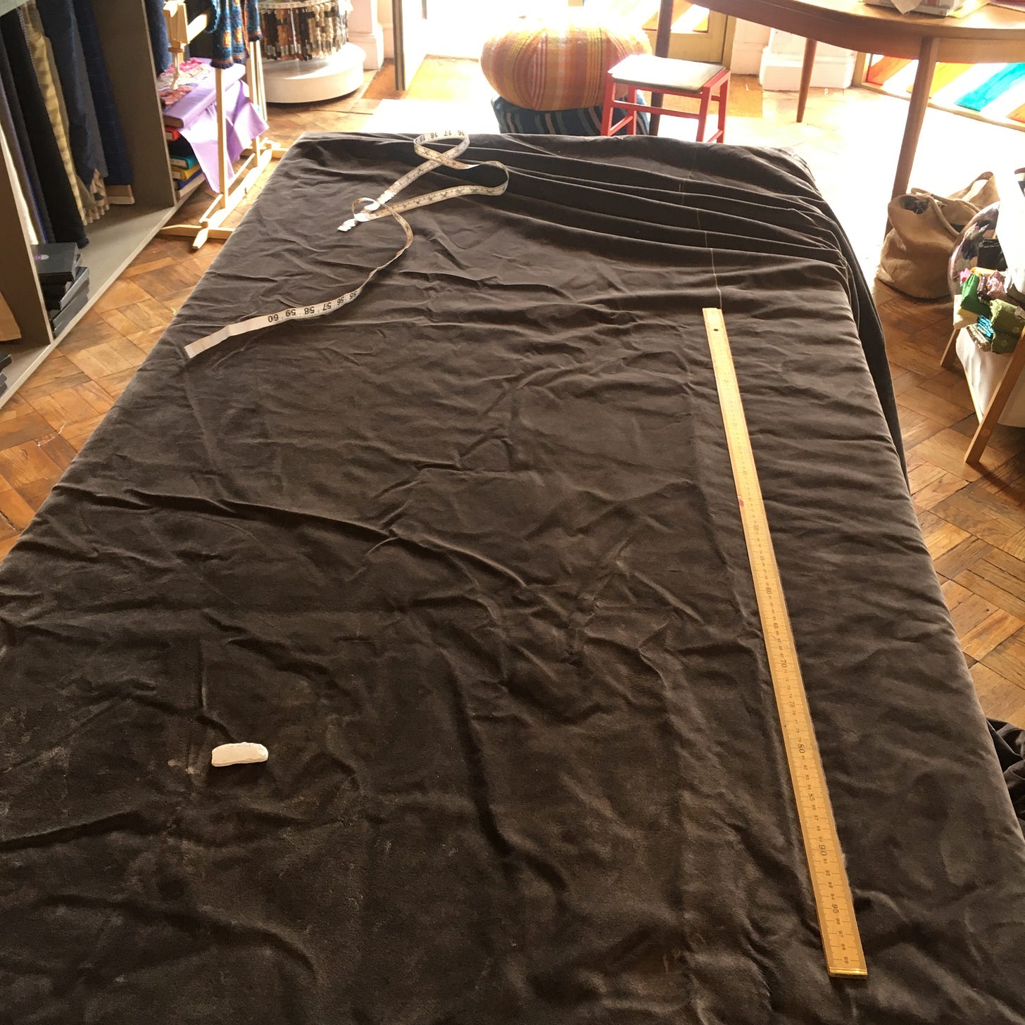 A large, brown velvet curtain on a cutting table, ready to be cut and sewn
