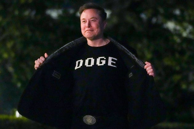 Elon Musk wearing a DOGE T-shirt. Elon Musk wearing a DOGE T-shirt.