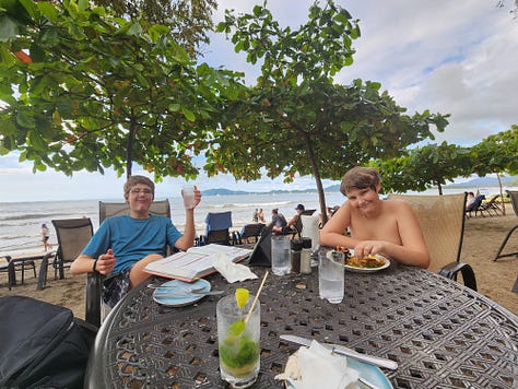 6 images of two boys homeschooling from different places, including an RV and on the beach