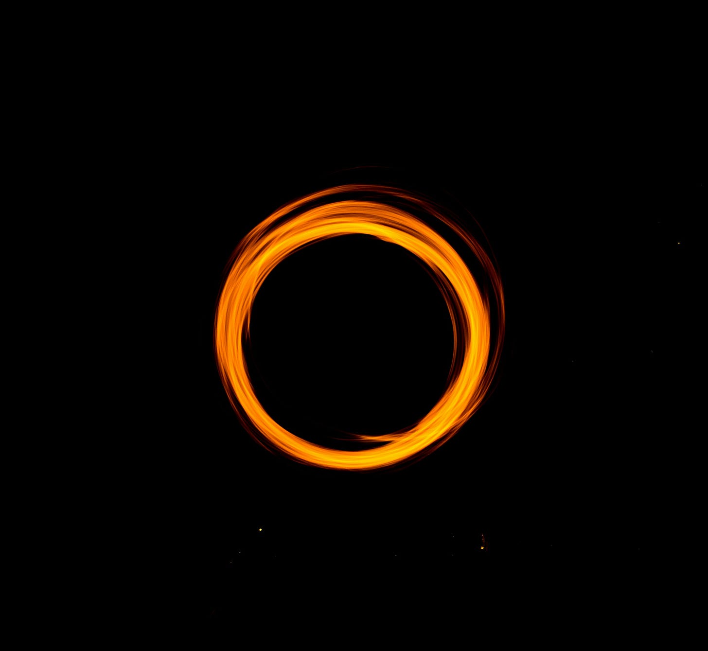 A ring of orange light stands stark against a black background. A ring of orange light stands stark against a black background.