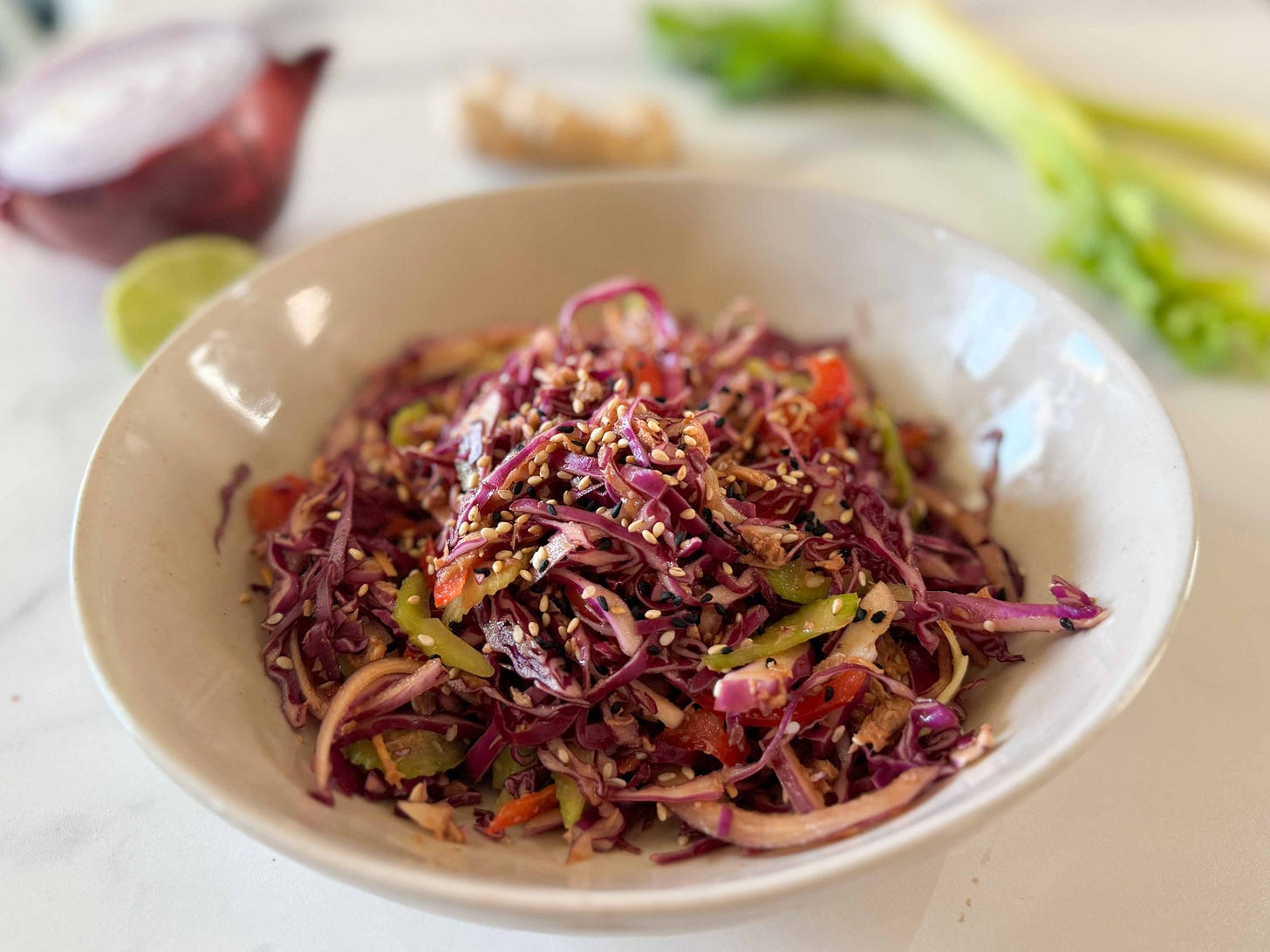 a bowl of cabbage-and-tuna salad with vegetables in the background