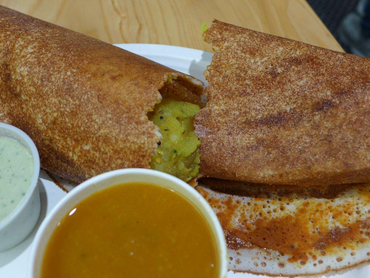 A dosa cracked open to show the potato filling.