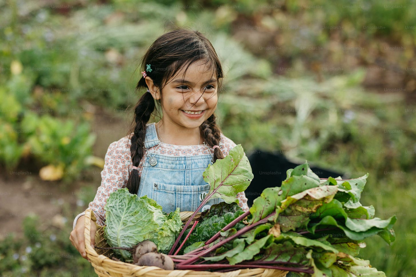 A little girl holding a basket full of vegetables