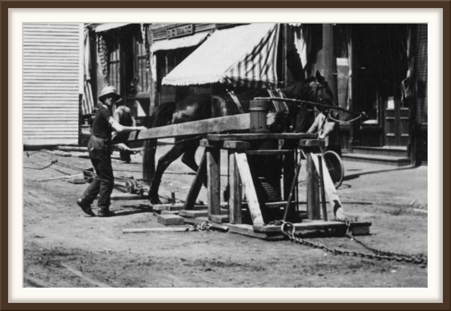 Close view of a wooden capstan drum with rope wound on it, a long sweep arm, and one horse Close view of a wooden capstan drum with rope wound on it, a long sweep arm, and one horse