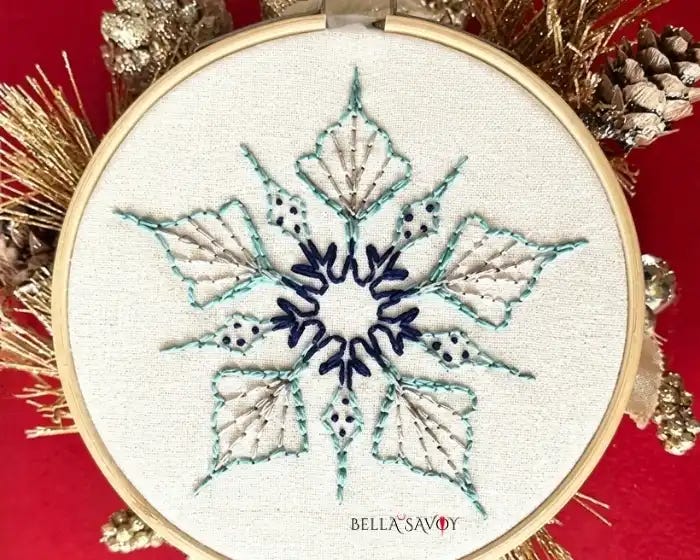 5 pointed snowflake embroidery on hooped fabric. Red background
