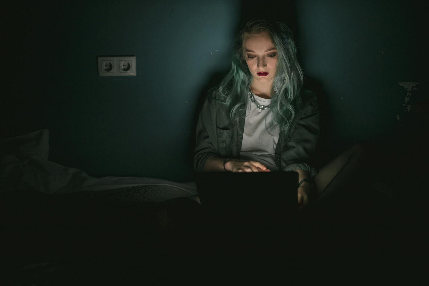 Photo of a woman in the dark, her face eerily illuminated by the screen of her laptop Photo of a woman in the dark, her face eerily illuminated by the screen of her laptop