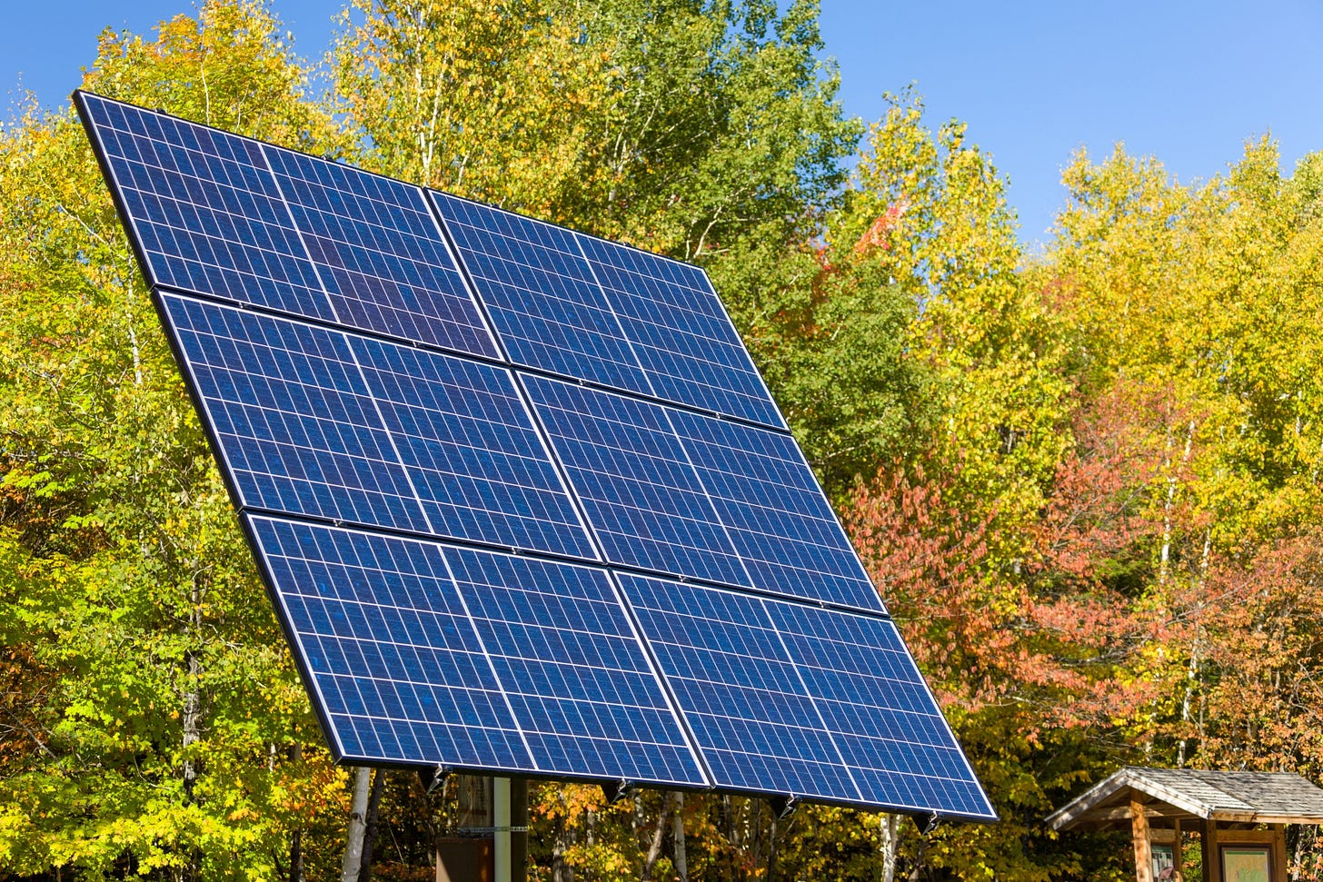 photo of a small solar array in front of green trees