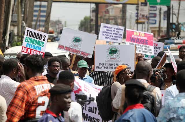 A group of people protesting on the street while holding placards A group of people protesting on the street while holding placards