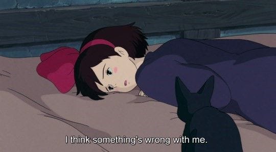 This may contain: a person laying in bed with a black cat next to her and the caption reads i think something's wrong with me